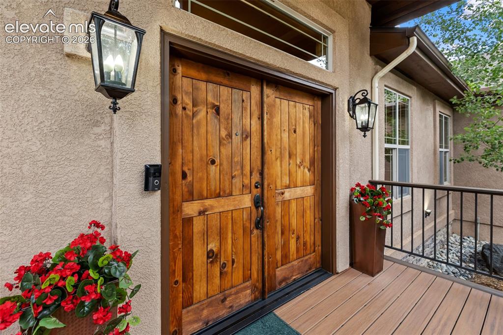 Image 4 of 50: Natural wood double door entry with covered front porch and Trex decking.