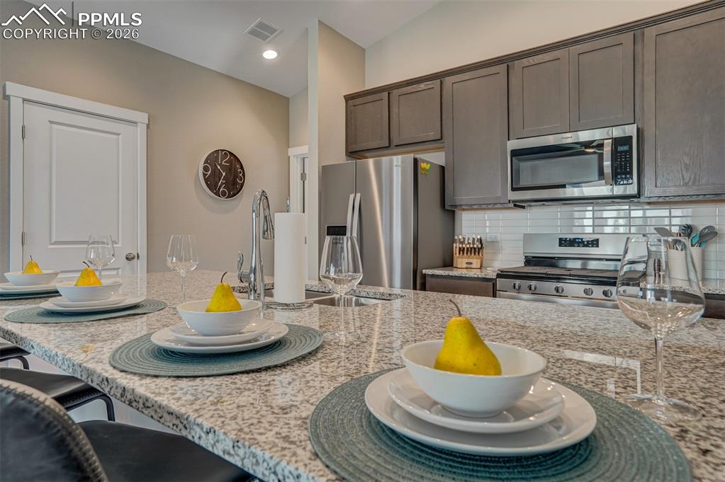 Image 16 of 46: Kitchen featuring a kitchen breakfast bar, stainless steel appliances, ligh