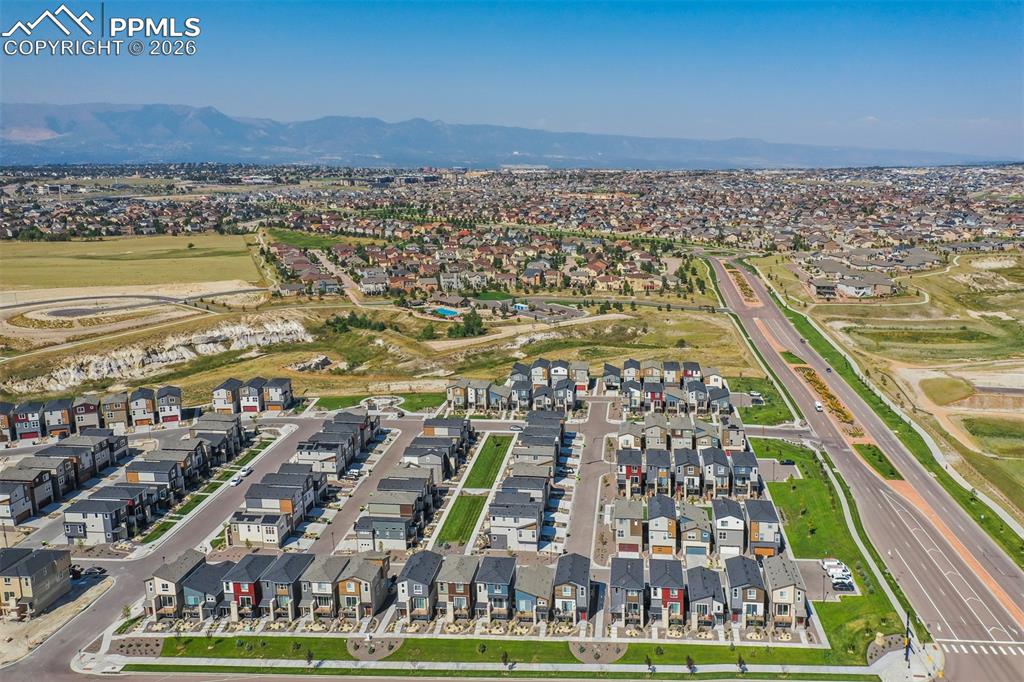 Image 45 of 46: Aerial perspective of suburban area featuring a mountain backdrop and a loc