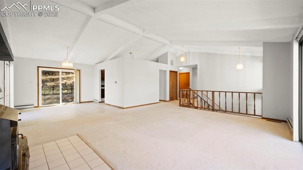 Image 14 of 50: Unfurnished living room featuring light colored carpet, beam ceiling, light