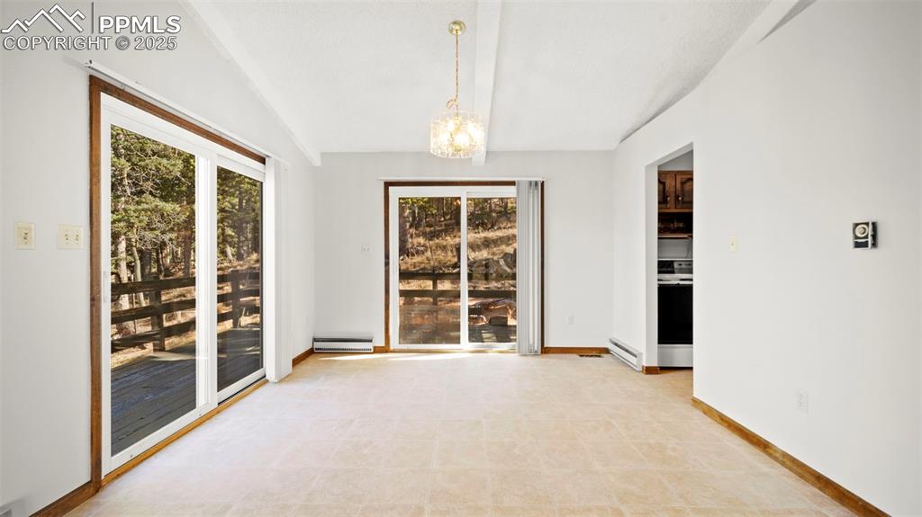 Image 15 of 50: Unfurnished room with a chandelier, baseboard heating, vaulted ceiling, and