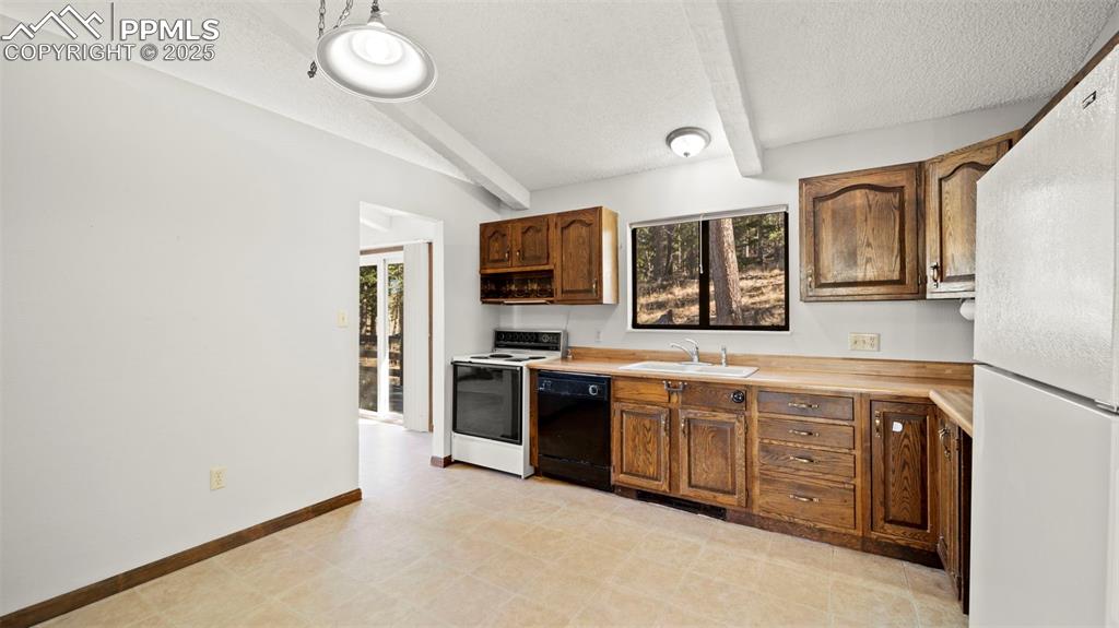 Image 18 of 50: Kitchen with freestanding refrigerator, beam ceiling, electric range oven, 