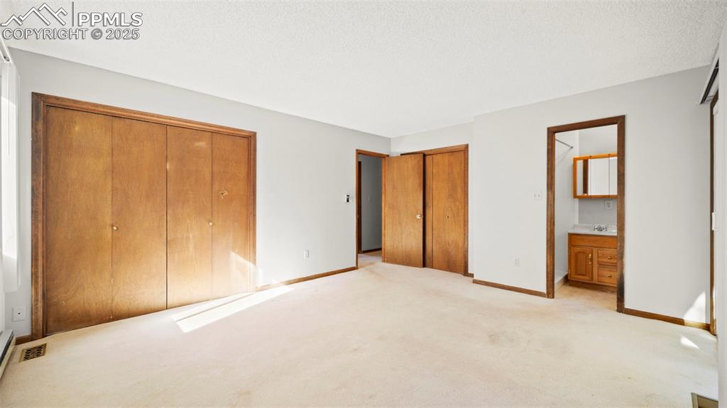 Image 23 of 50: Unfurnished bedroom featuring carpet flooring, two closets, connected bathr