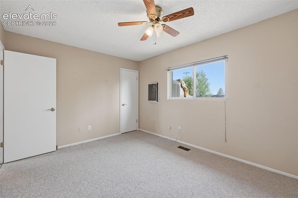 Image 29 of 36: Textured ceiling, wall-to-wall carpeting, single window, and a ceiling fan
