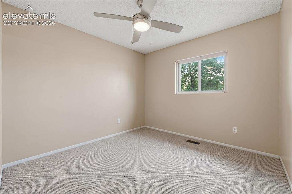 Image 30 of 36: Neutral tone wall paint, textured carpeting, bi-fold closet doors, and a ce