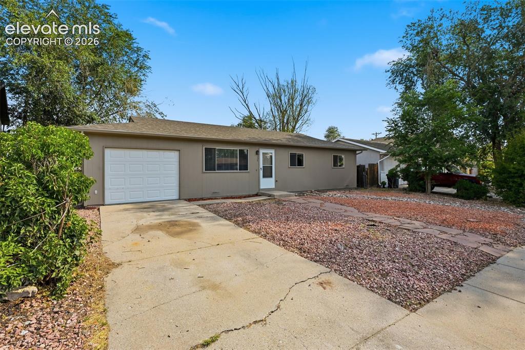 Image 6 of 36: Single-story exterior with an attached garage, covered entry, and a gravel 