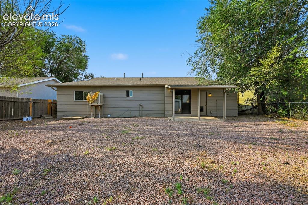 Image 8 of 36: Expansive backyard featuring a gravel and sparse lawn surface, partial wood
