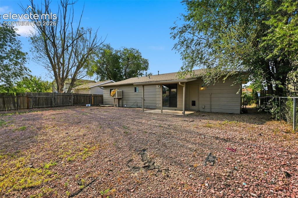 Image 9 of 36: Expansive rear yard featuring a gravel patio, mature trees, and a detached