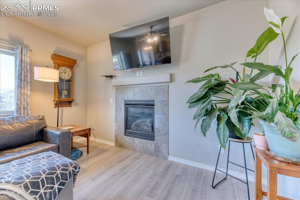 Image 13 of 39: Living room with wood finished floors and a tiled fireplace