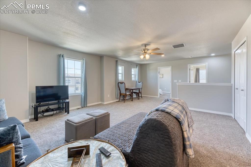 Image 17 of 39: Living room with carpet flooring, a ceiling fan, a textured ceiling, and re
