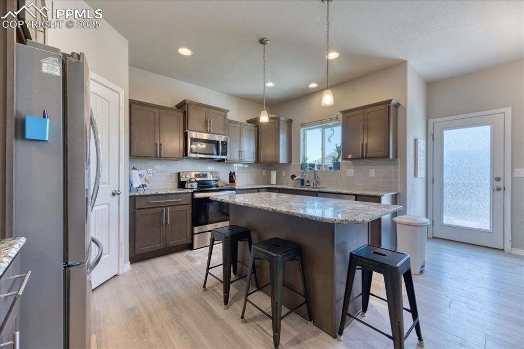 Image 2 of 39: Kitchen with appliances with stainless steel finishes, a kitchen bar, taste