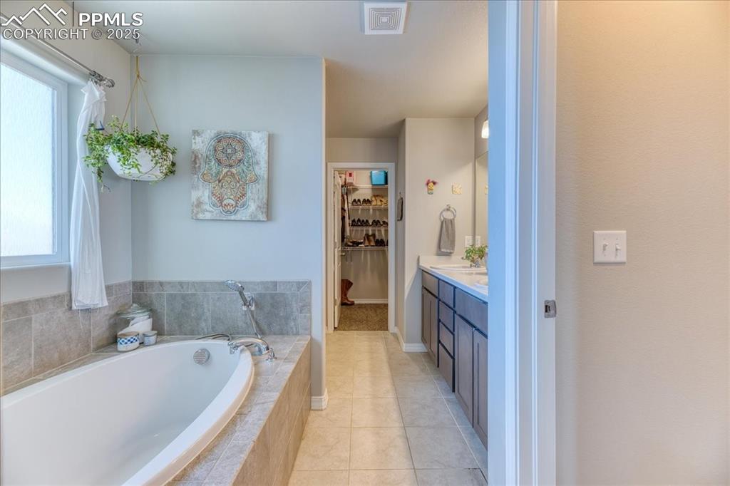 Image 23 of 39: Full bath featuring a bath, vanity, a walk in closet, tile patterned floors