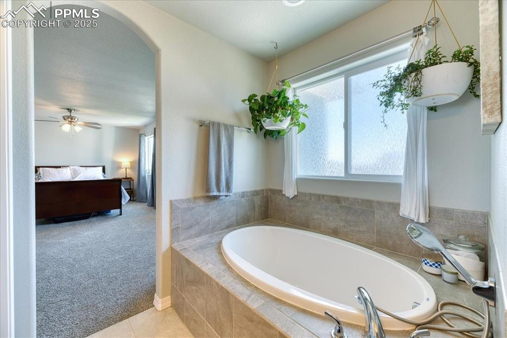 Image 26 of 39: Ensuite bathroom with a bath, tile patterned flooring, and a ceiling fan