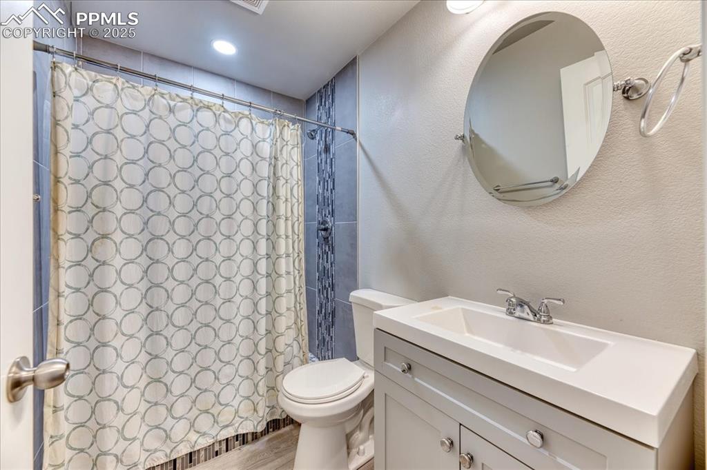 Image 31 of 39: Bathroom featuring vanity, a shower with shower curtain, and wood finished 