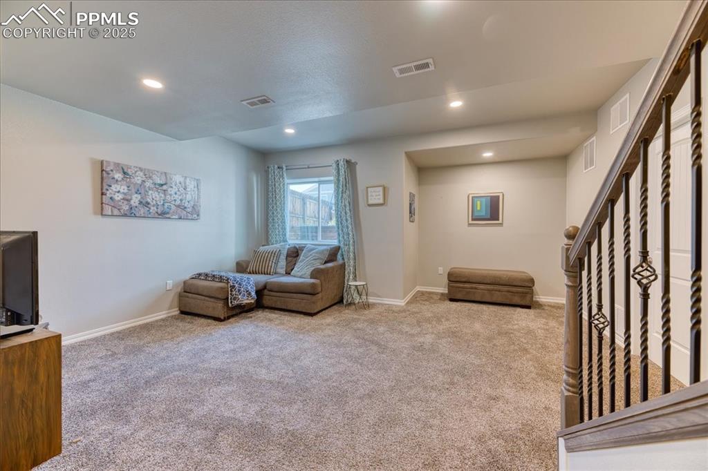 Image 32 of 39: Living room with carpet flooring, recessed lighting, and stairway