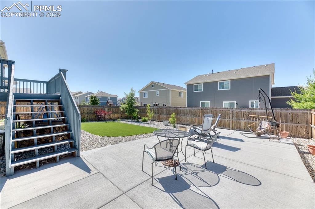 Image 34 of 39: Fenced backyard with a patio area, stairs, and a residential view