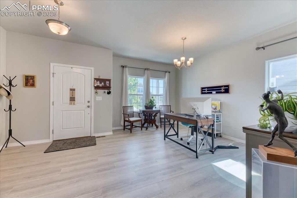 Image 8 of 39: Entrance foyer with light wood finished floors and a chandelier