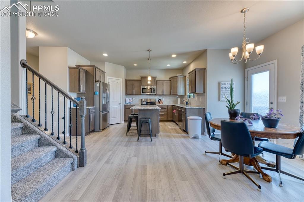 Image 9 of 39: Dining area featuring light wood-style flooring, a chandelier, stairway, an