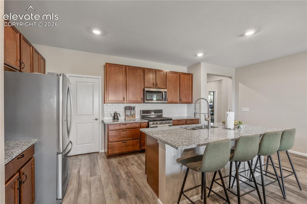 Image 11 of 38: Kitchen featuring a central island with integrated sink, granite countertop
