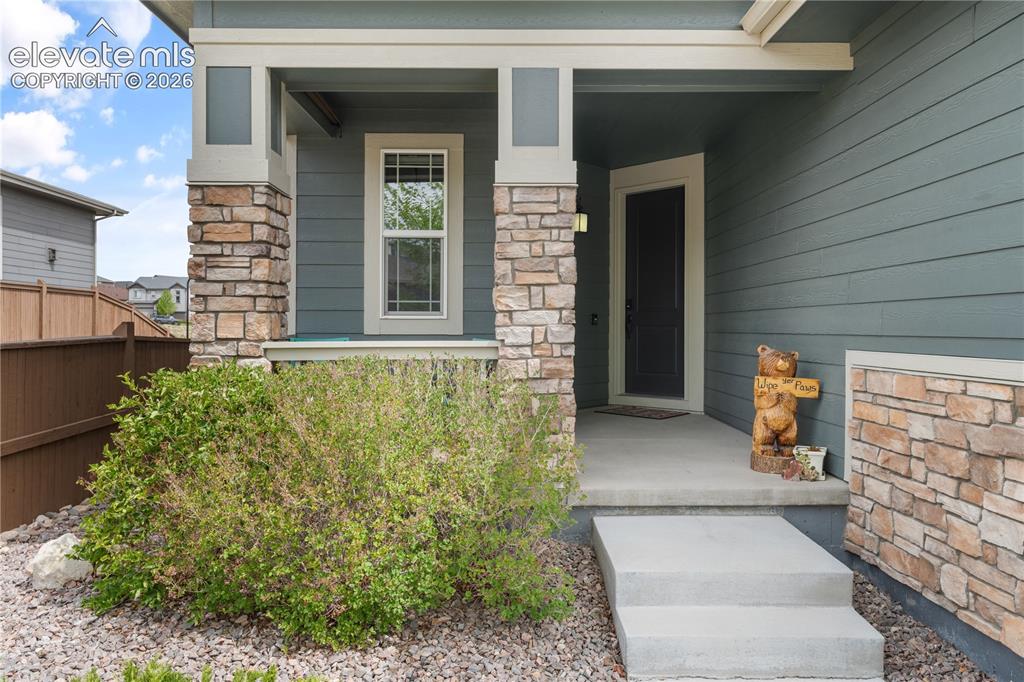 Image 2 of 38: Entryway featuring a dark paneled door, stone facade accents, and horizonta