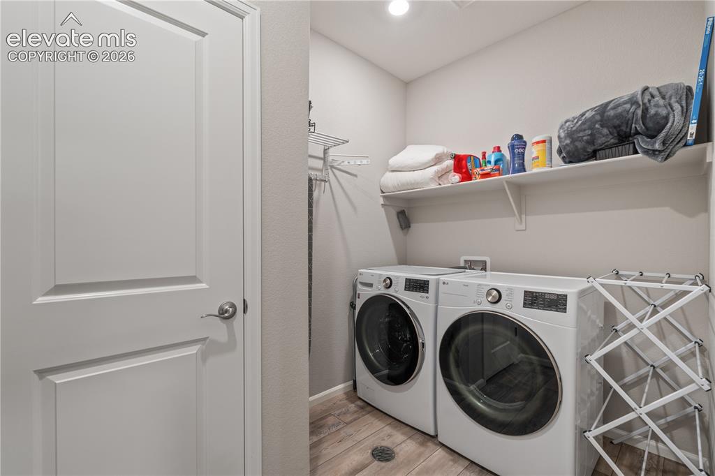 Image 29 of 38: Dedicated laundry area featuring wood-finish flooring, two large wall-mount