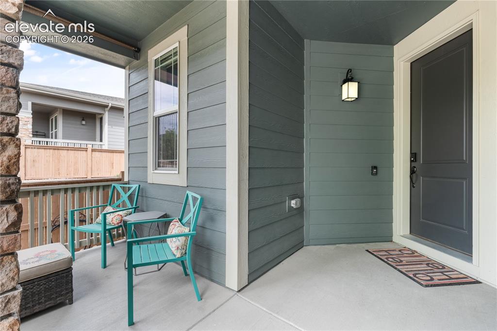 Image 3 of 38: Covered porch featuring durable concrete flooring, stone column detailing, 
