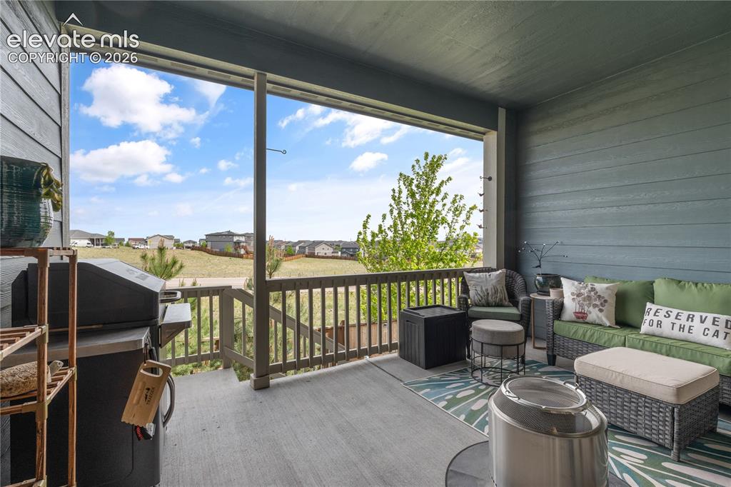 Image 31 of 38: Covered outdoor deck with grey flooring and wood railing