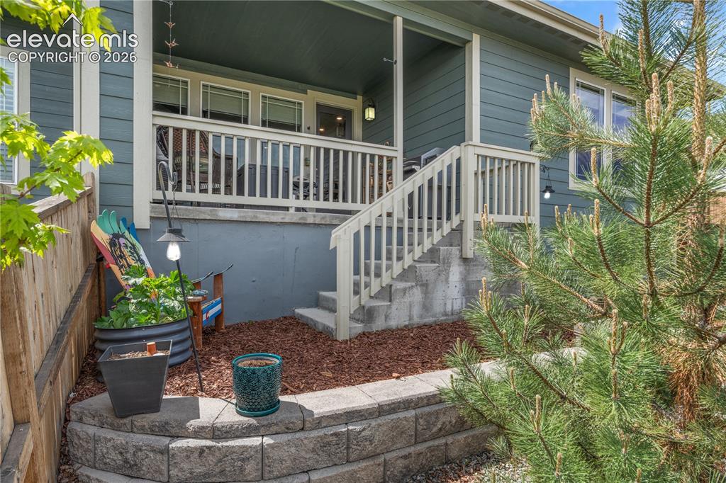 Image 33 of 38: Exterior deck with white railing, concrete stairs, and a stone retaining wa