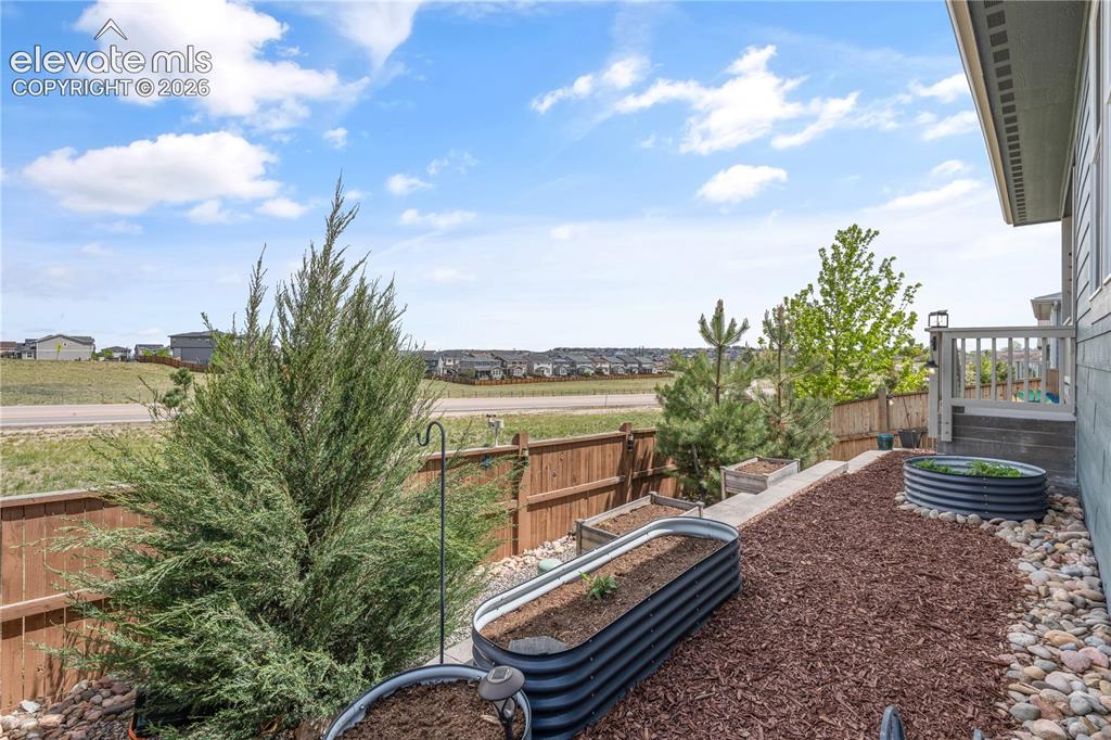 Image 34 of 38: Backyard featuring a wooden privacy fence and tiered landscaping with wood 