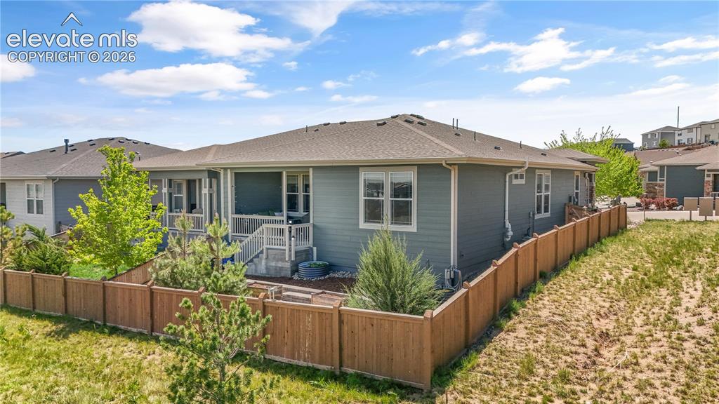 Image 36 of 38: Rear exterior featuring light blue siding, a covered patio with white raili