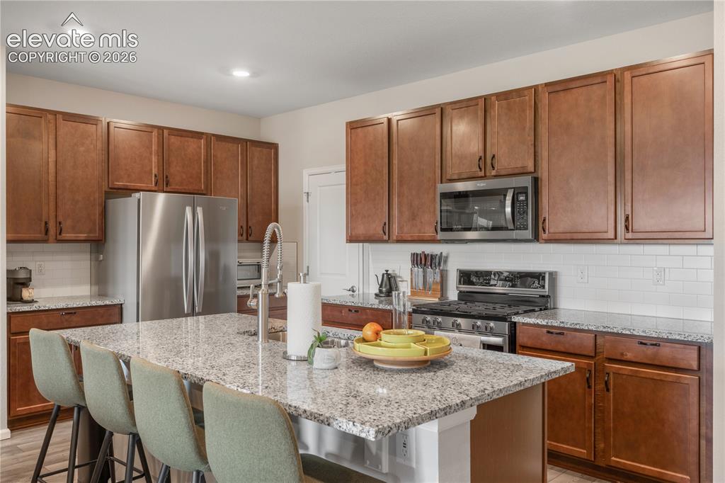 Image 8 of 38: Kitchen featuring a central island with a granite-style countertop, stainle