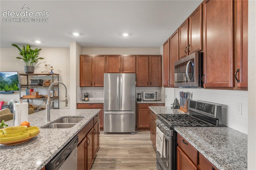 Image 9 of 38: Open-concept kitchen featuring granite countertops, wood-finish cabinetry, 