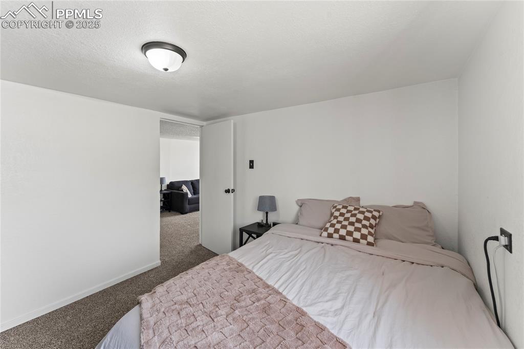 Image 13 of 26: Carpeted bedroom with a textured ceiling and baseboards