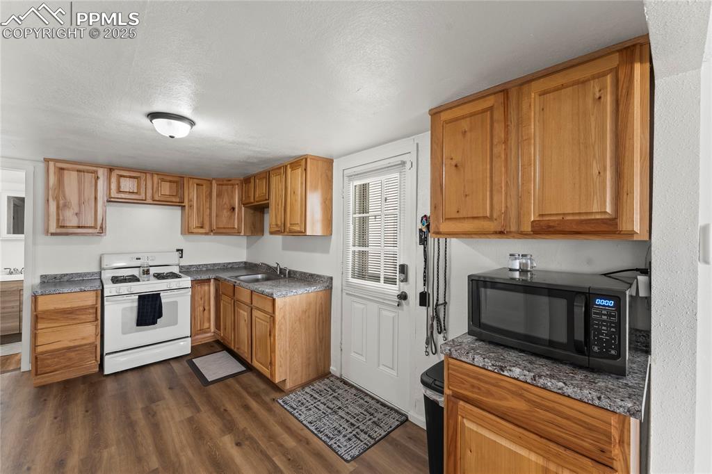 Image 15 of 26: Kitchen with white range with gas cooktop, dark wood-type flooring, a textu