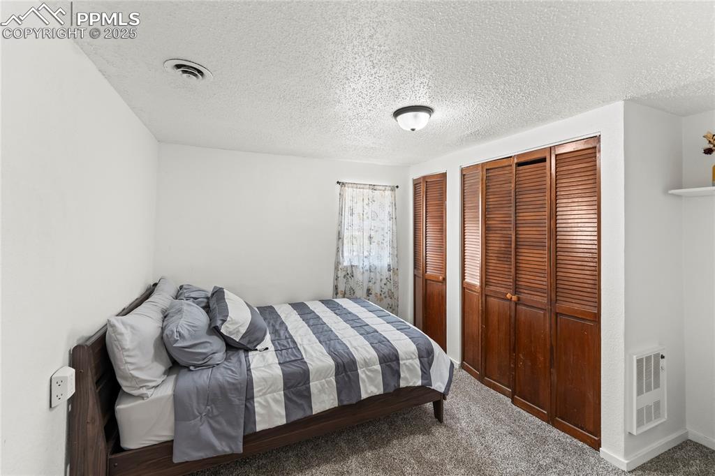 Image 18 of 26: Bedroom with carpet, two closets, a textured ceiling, and heating unit
