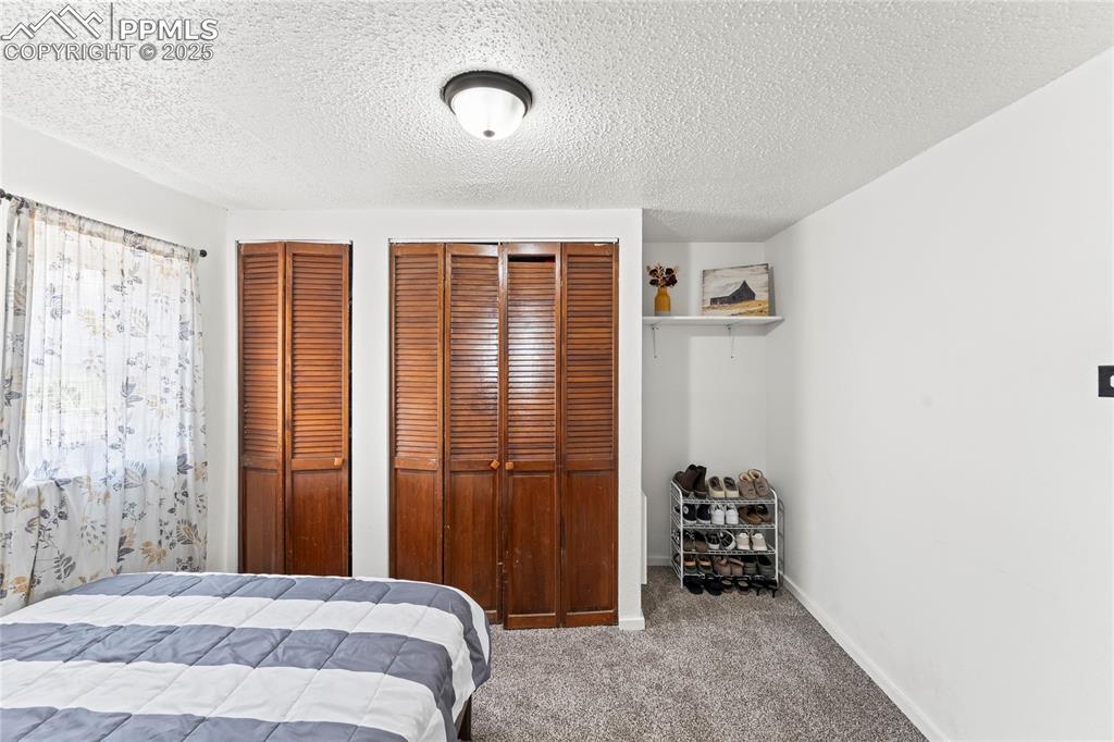 Image 19 of 26: Bedroom with multiple closets, carpet, and a textured ceiling