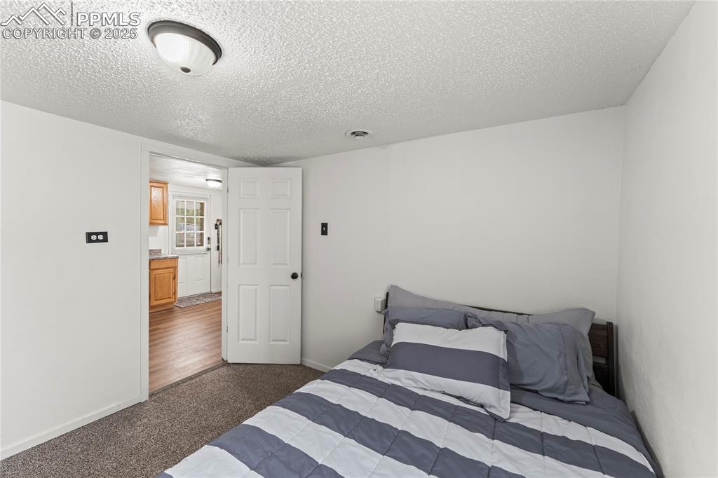 Image 20 of 26: Bedroom with dark colored carpet and a textured ceiling