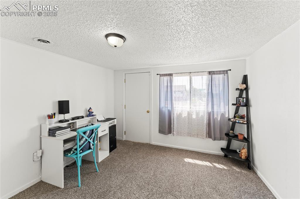Image 8 of 26: Carpeted home office featuring a textured ceiling and baseboards