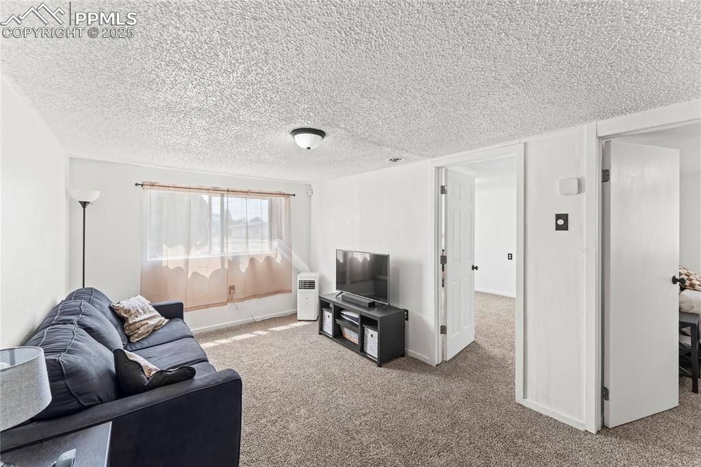 Image 9 of 26: Carpeted living area with a textured ceiling and baseboards