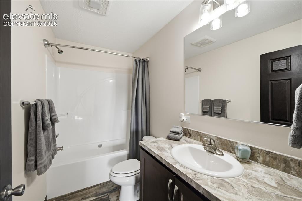 Image 15 of 26: Bathtub with shower, single vanity with integrated sink, dark wood-finish c