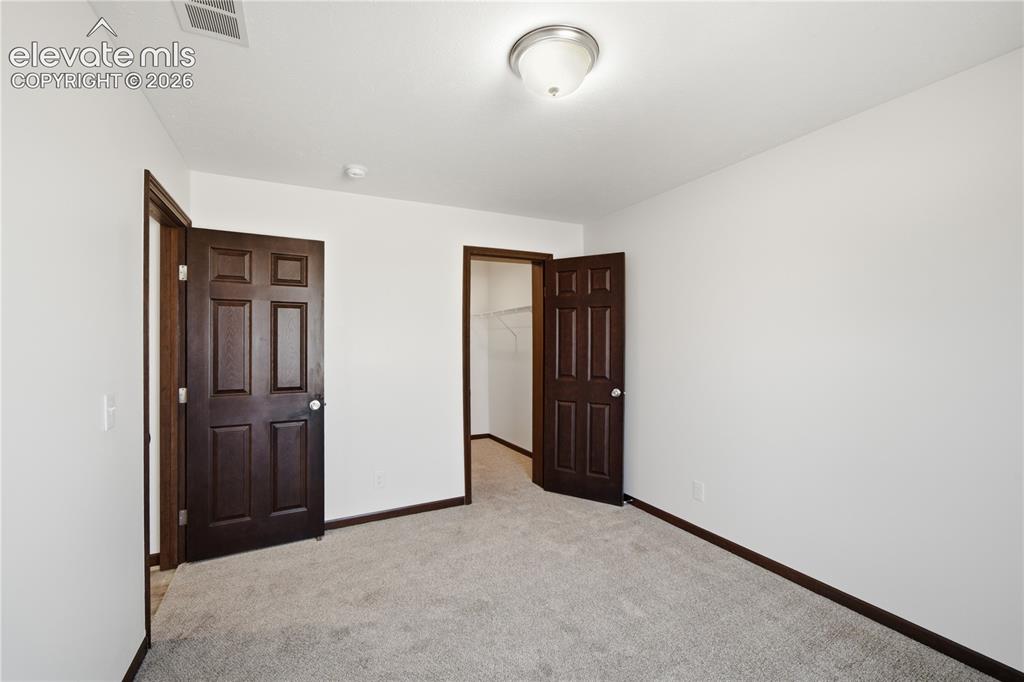 Image 16 of 26: Neutral white wall finish, plush grey carpeting, dark wood-finish paneled d