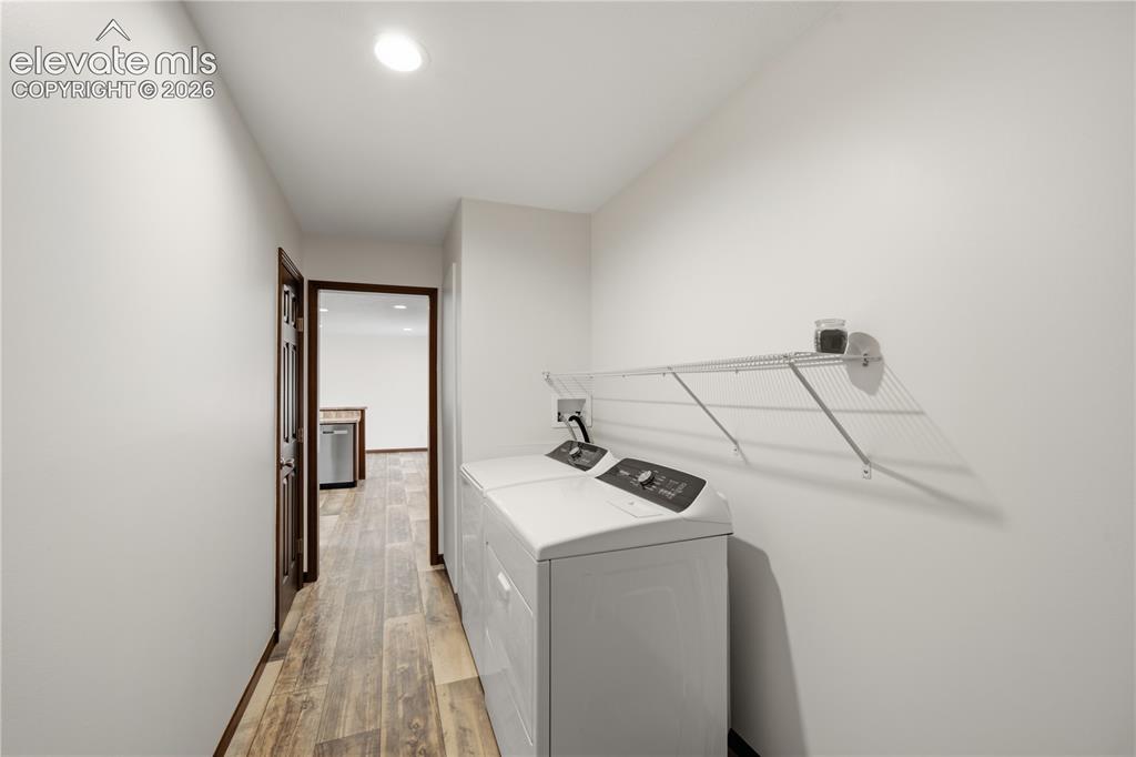 Image 17 of 26: Laundry area featuring wood-finish flooring, white walls, and a wire storag