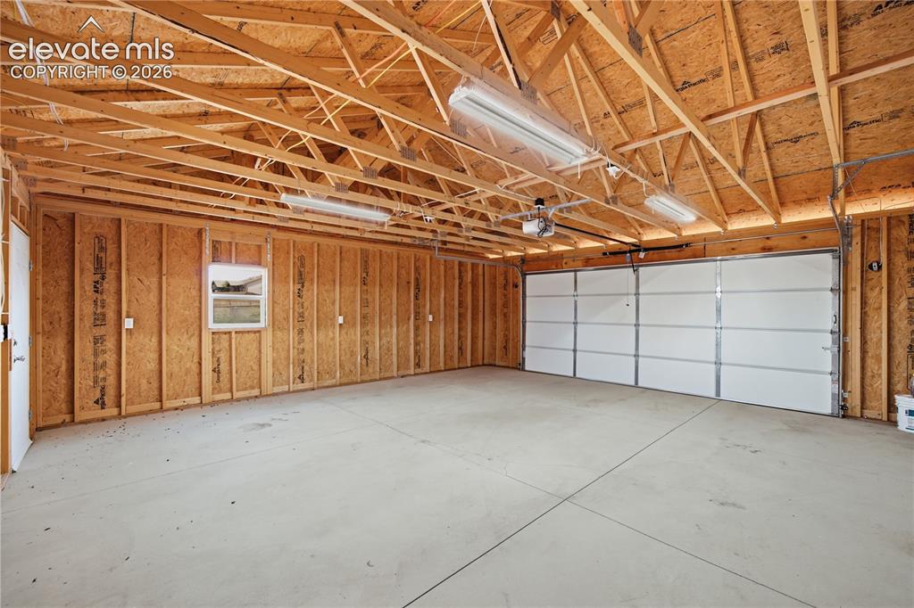 Image 18 of 26: Spacious garage featuring exposed wood-beam ceiling construction, polished