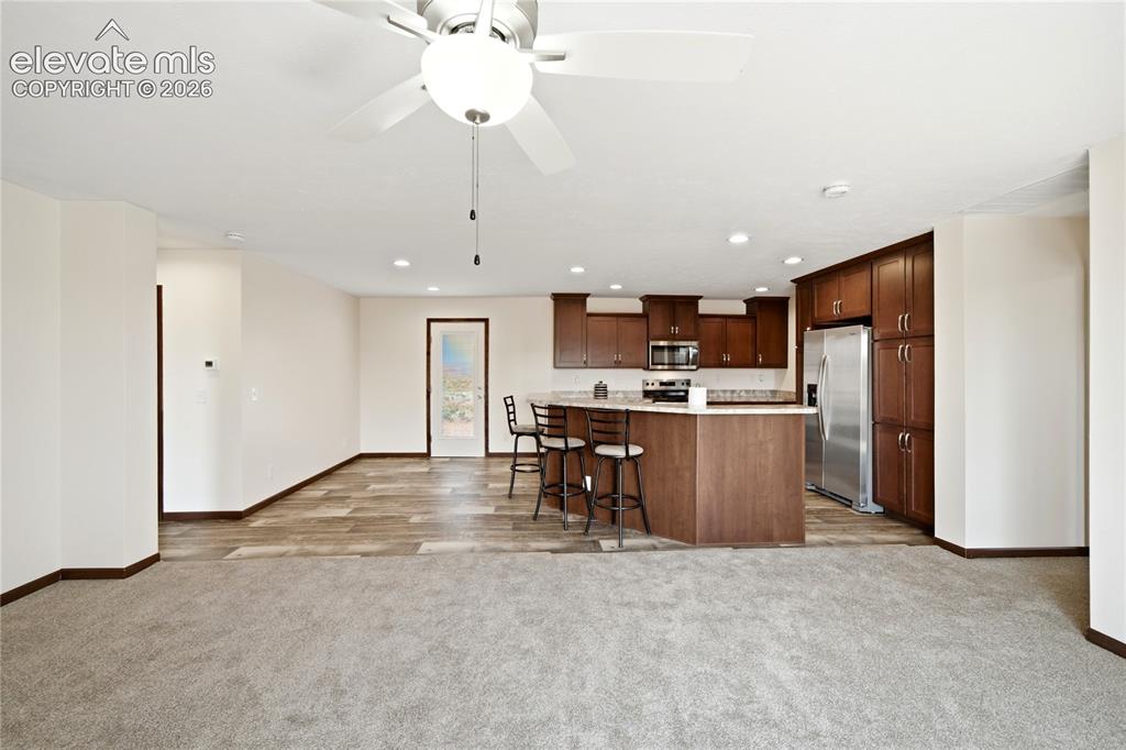 Image 2 of 26: Open-concept living area featuring warm wood-finish cabinetry with stainles