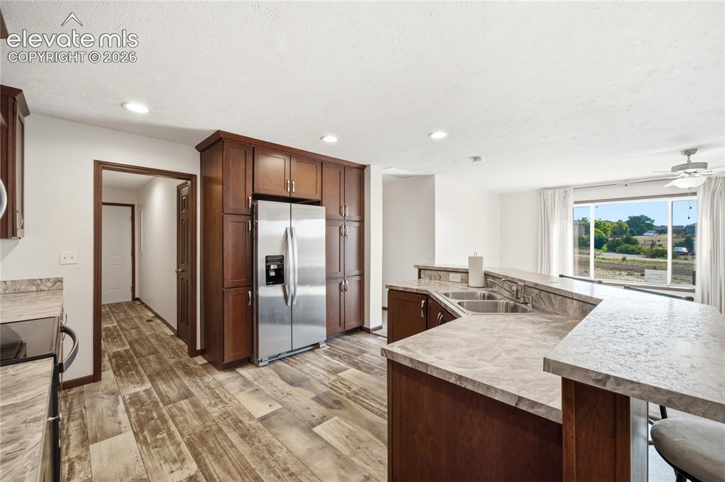 Image 8 of 26: Kitchen featuring dark wood-finish cabinetry, stainless steel refrigerator,