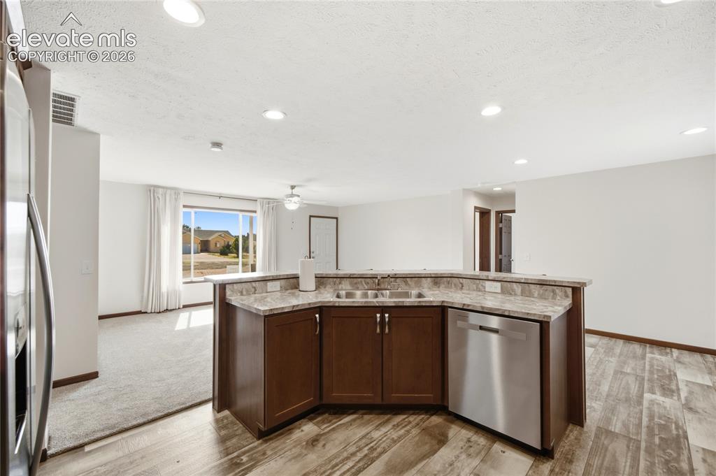 Image 9 of 26: Open-concept kitchen island featuring rich wood cabinetry with stainless st