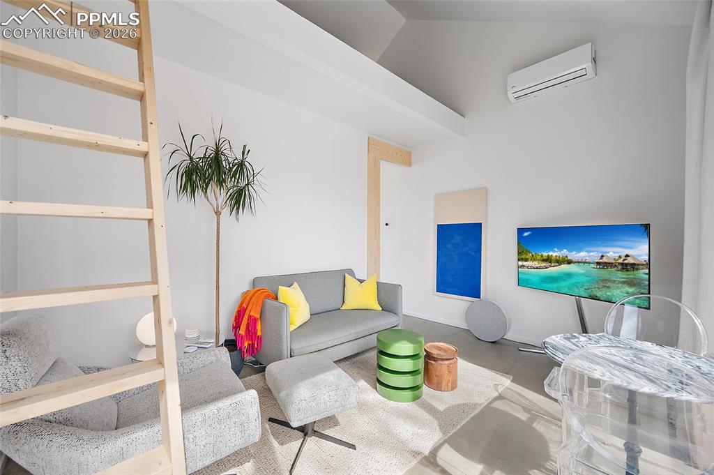 Image 39 of 50: Ladder leads to the loft area. Open floor plan with living area and kitchen