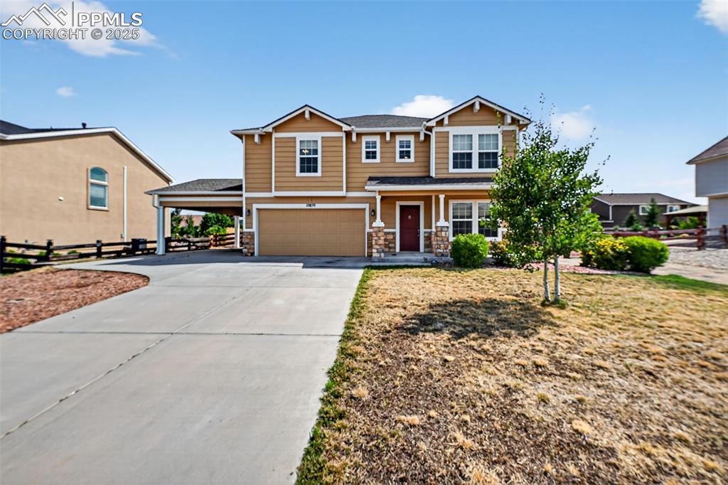 Caption: Craftsman-style home with stone siding, concrete driveway, covered porch, and a garage