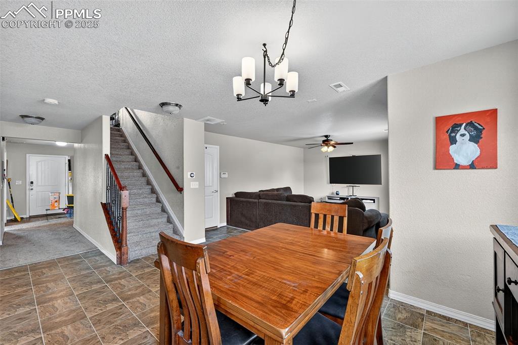 Image 12 of 33: Dining space featuring stone finish floors, stairway, a chandelier, ceiling