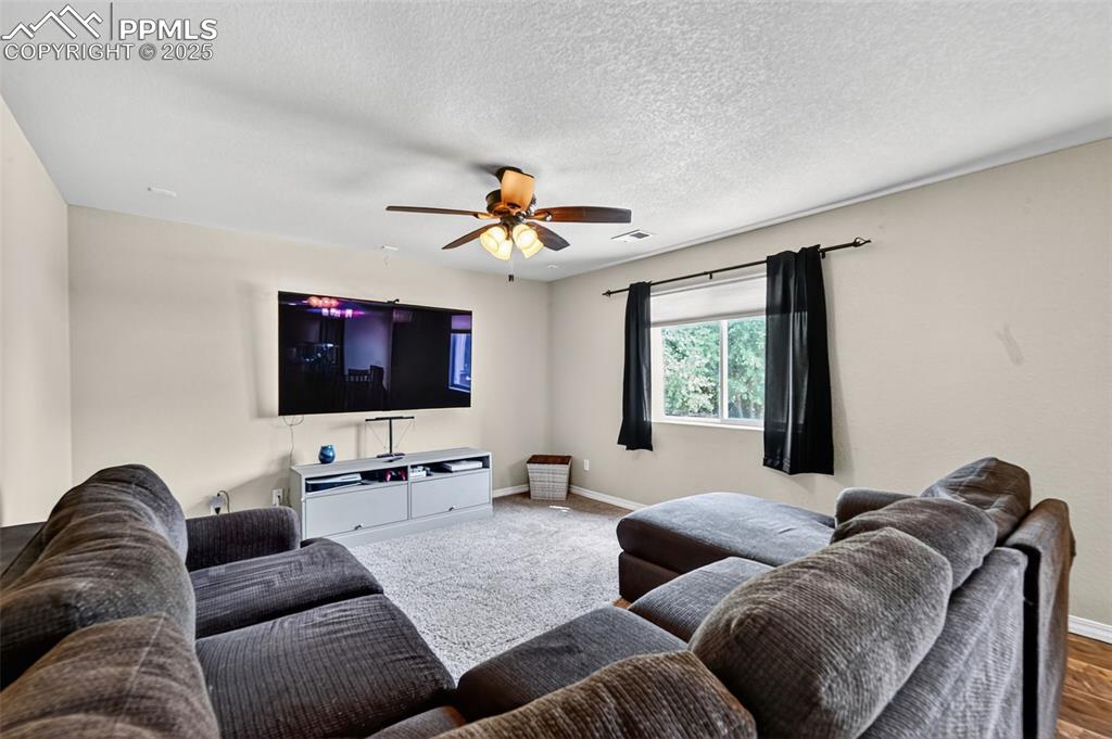 Image 16 of 33: Carpeted living area featuring a ceiling fan and a textured ceiling